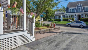 A residential street with a porch, American flags, and a red fire hydrant.