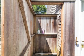 A narrow wooden structure with a door and a small shelf.