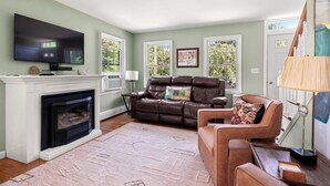 A living room with a fireplace, leather sofa, and a flat-screen TV.
