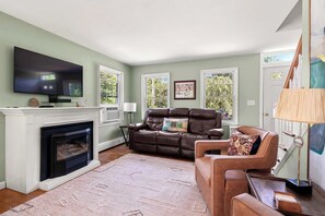 A living room with a fireplace, leather sofa, and a flat-screen TV.