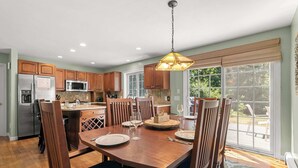 A modern kitchen with wooden cabinets, stainless steel appliances, and a dining area with a table set for two.