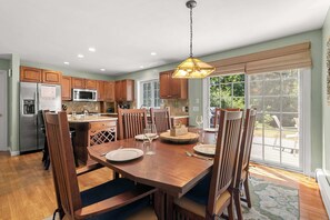 A modern kitchen with wooden cabinets, stainless steel appliances, and a dining area with a table set for two.