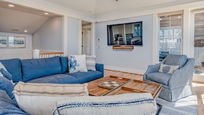 A modern living room with a blue sofa, a patterned armchair, and a wooden coffee table. - Reverse floor plan home with ocean views, updated kitchen and bathrooms! (Bald Head Island)