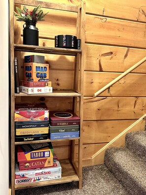 A wooden shelf with various board games and a small potted plant. - BEST 6br Ski-In+Out w. Hot Tub->Gear rm, PS-5, Fun+Lux (Snowshoe)