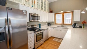 Una cocina moderna con electrodomésticos de acero inoxidable, armarios blancos y piso de madera.