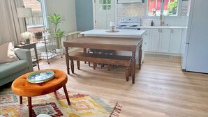 Una cocina moderna con armarios blancos, una mesa de comedor de madera y una alfombra pequeña.
