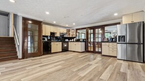 Una cocina amplia con piso de madera, electrodomésticos de acero inoxidable y una isla central.