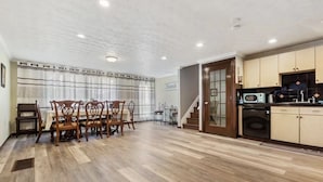 Un comedor amplio con una mesa y sillas de madera, una cocina con electrodomésticos modernos y una escalera que conduce a otro nivel.
