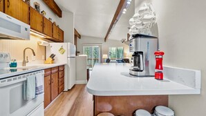 Una cocina moderna con armarios de madera, encimera blanca y cafetera integrada.