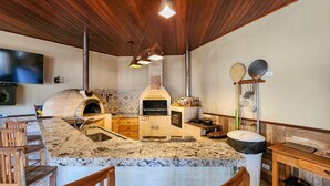 A kitchen with a built-in oven, wooden bar, and a stone countertop.