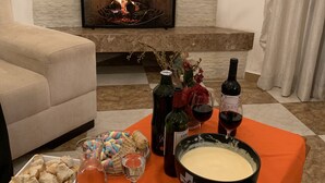 A cozy living room with a fireplace, a dining table set with food and drinks, and a comfortable sofa.