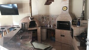 A kitchen with two brick ovens, a countertop with a sink, and a wall-mounted clock.