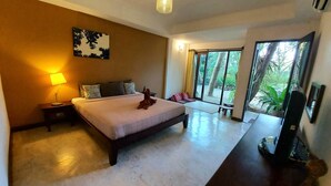 Habitación de hotel moderna con una cama grande, una lámpara de noche, un televisor de pantalla plana y vistas a zonas verdes a través de un gran ventanal corredero.