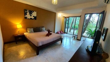 Quarto de hotel moderno com uma cama grande, luminária de cabeceira, TV de tela plana e vista para o verde através de uma grande porta de vidro deslizante.