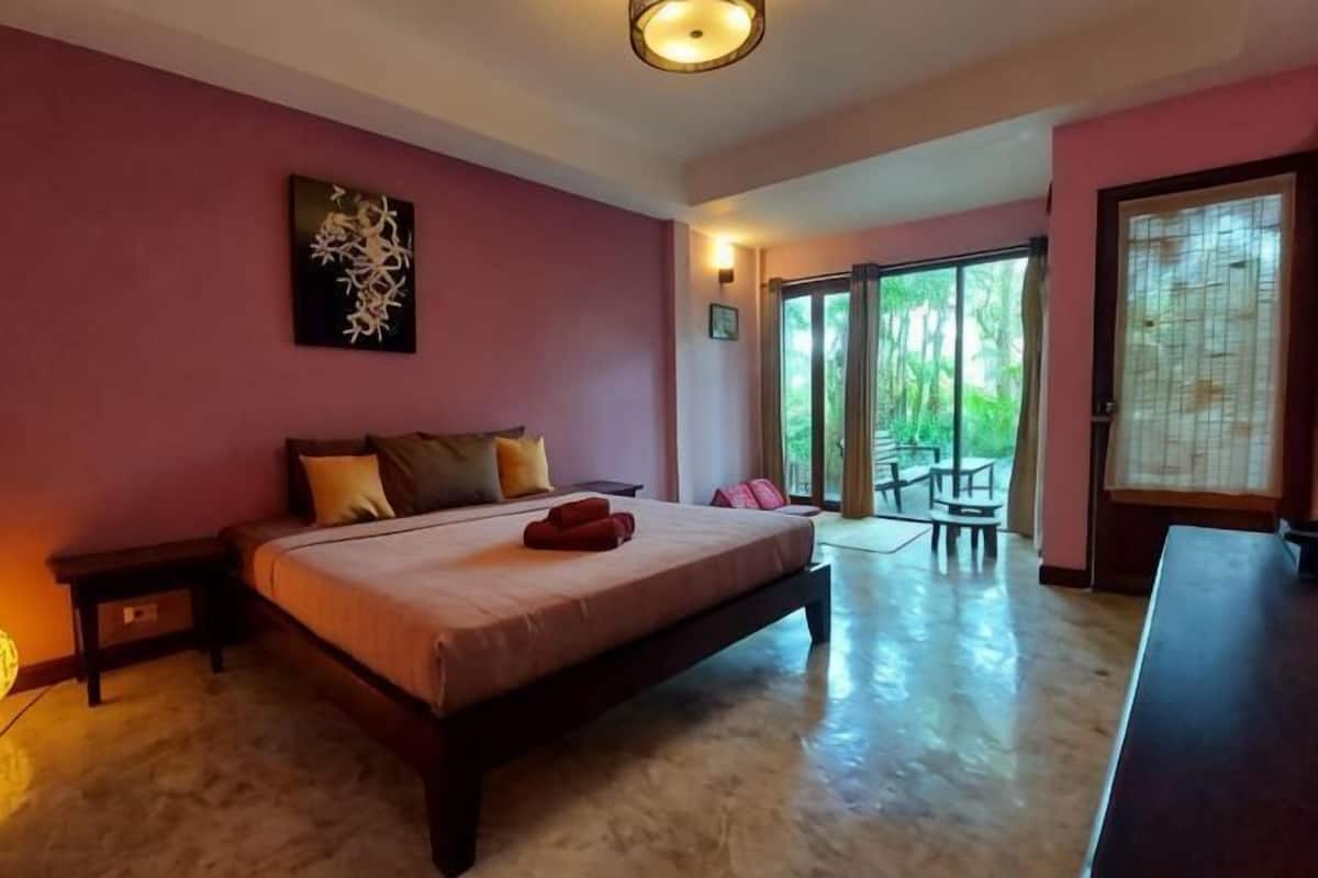 Une chambre à coucher avec un lit, une table de chevet, un tableau et une vue sur l’extérieur.