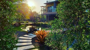 Una casa moderna con piscina, rodeada de exuberante vegetación y un sendero de madera.