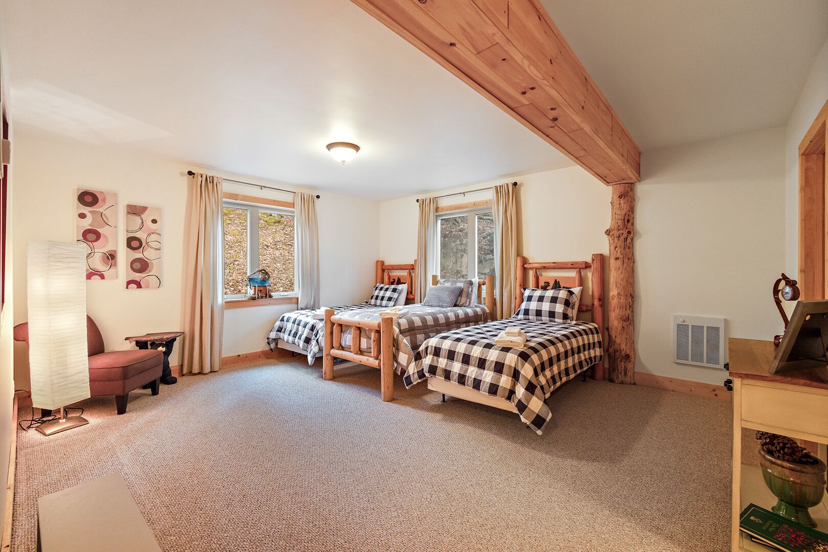 Ein Schlafzimmer mit zwei Betten, einer Holzbalkendecke, einem Fenster und einer Heizung.