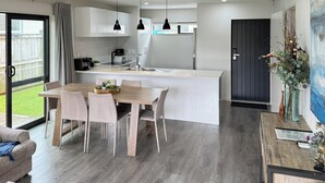 Eine moderne Küche mit Kochinsel, Pendelleuchten und einem Essbereich mit Holztisch und Stühlen.