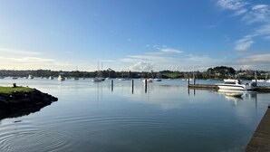 Ein Yachthafen mit mehreren angedockten Booten, ruhigem Wasser und wolkenlosem Himmel.