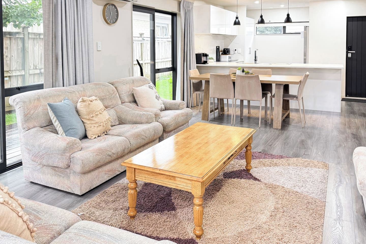 A modern living room with a sofa, coffee table, and dining area with chairs.