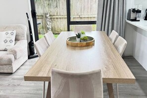 Un comedor moderno con una mesa de madera, sillas blancas y un pequeño centro de mesa con planta en maceta.