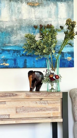 Une console en bois ornée d’une statuette d’éléphant décorative et de deux vases en verre contenant des fleurs.