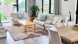 Ein modernes Wohnzimmer mit einer Sofagarnitur, einem Couchtisch und einem Esstisch.