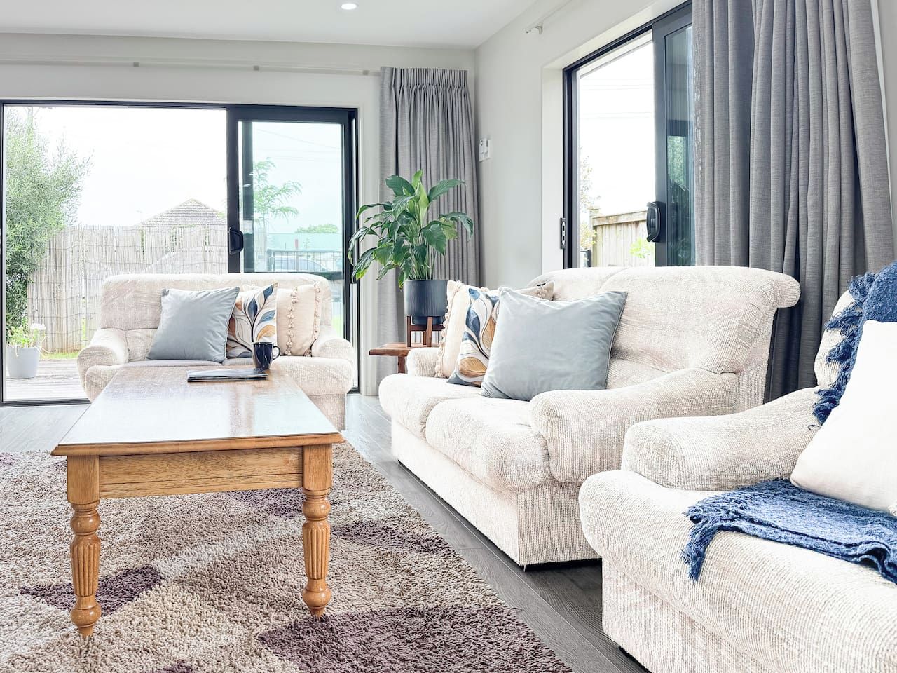 A modern living room with a sofa set, a coffee table, and a potted plant.