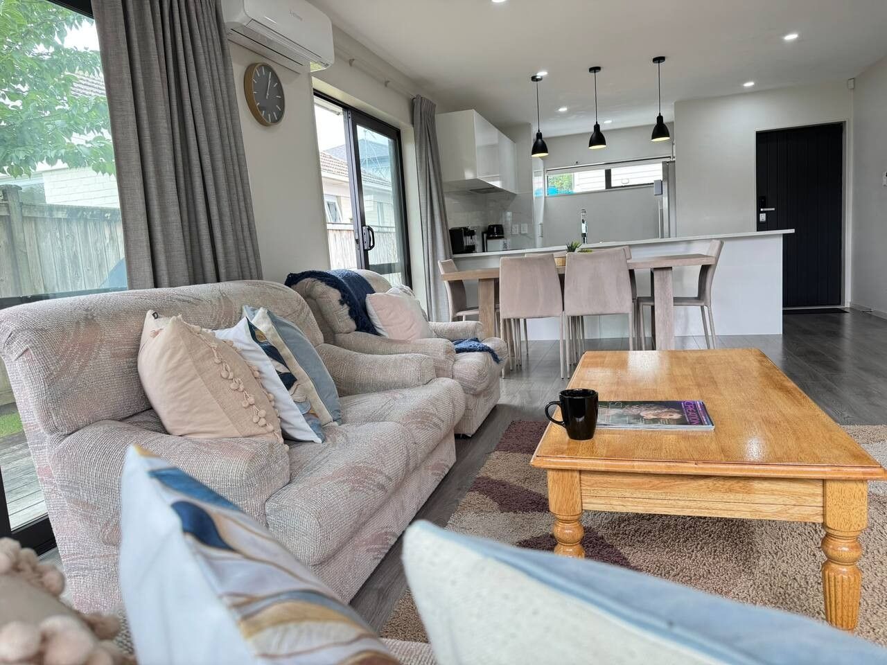 A modern living room with a sofa, coffee table, and a view of the kitchen.