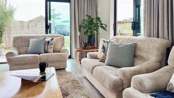 Ein Wohnzimmer mit zwei beigen Sesseln, einem Couchtisch und einer Topfpflanze.