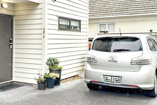 A white Toyota car parked in front of a house with a number '40C' on the wall.