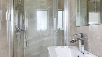 A modern bathroom with a glass-enclosed shower, a white sink, and a large mirror.