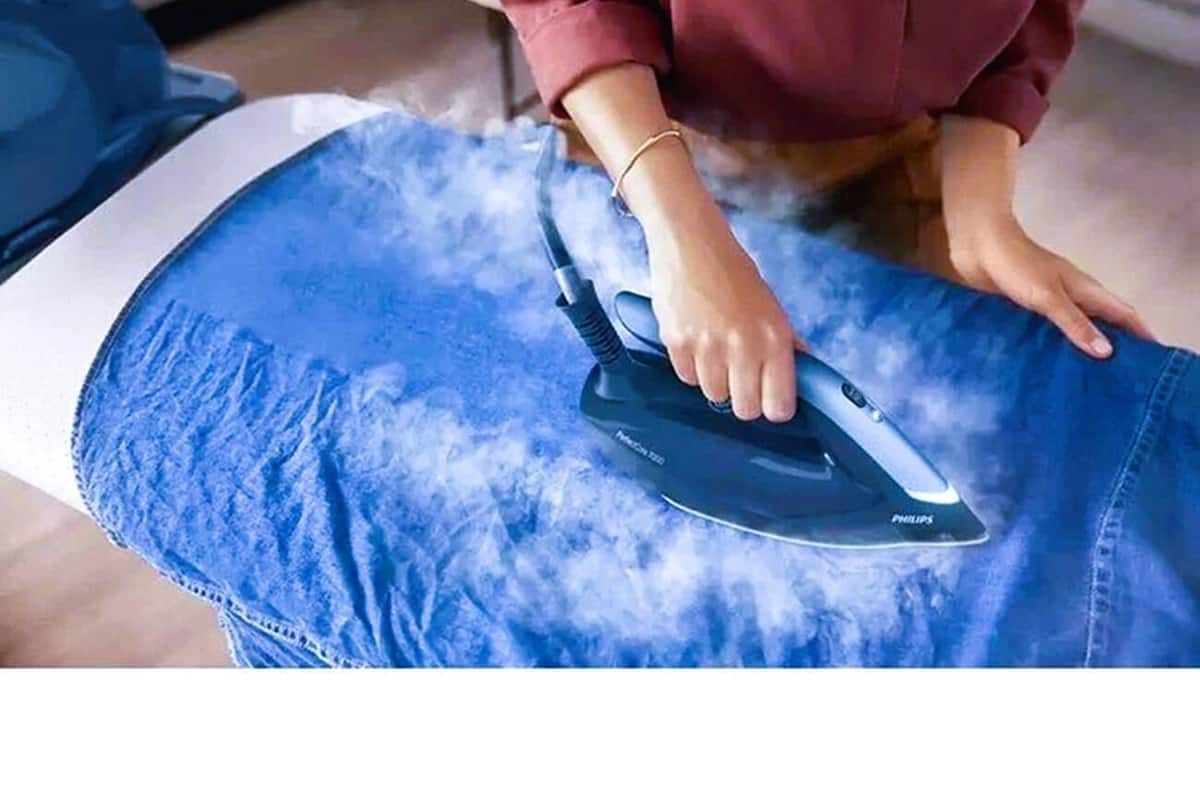 A person ironing a blue garment.
