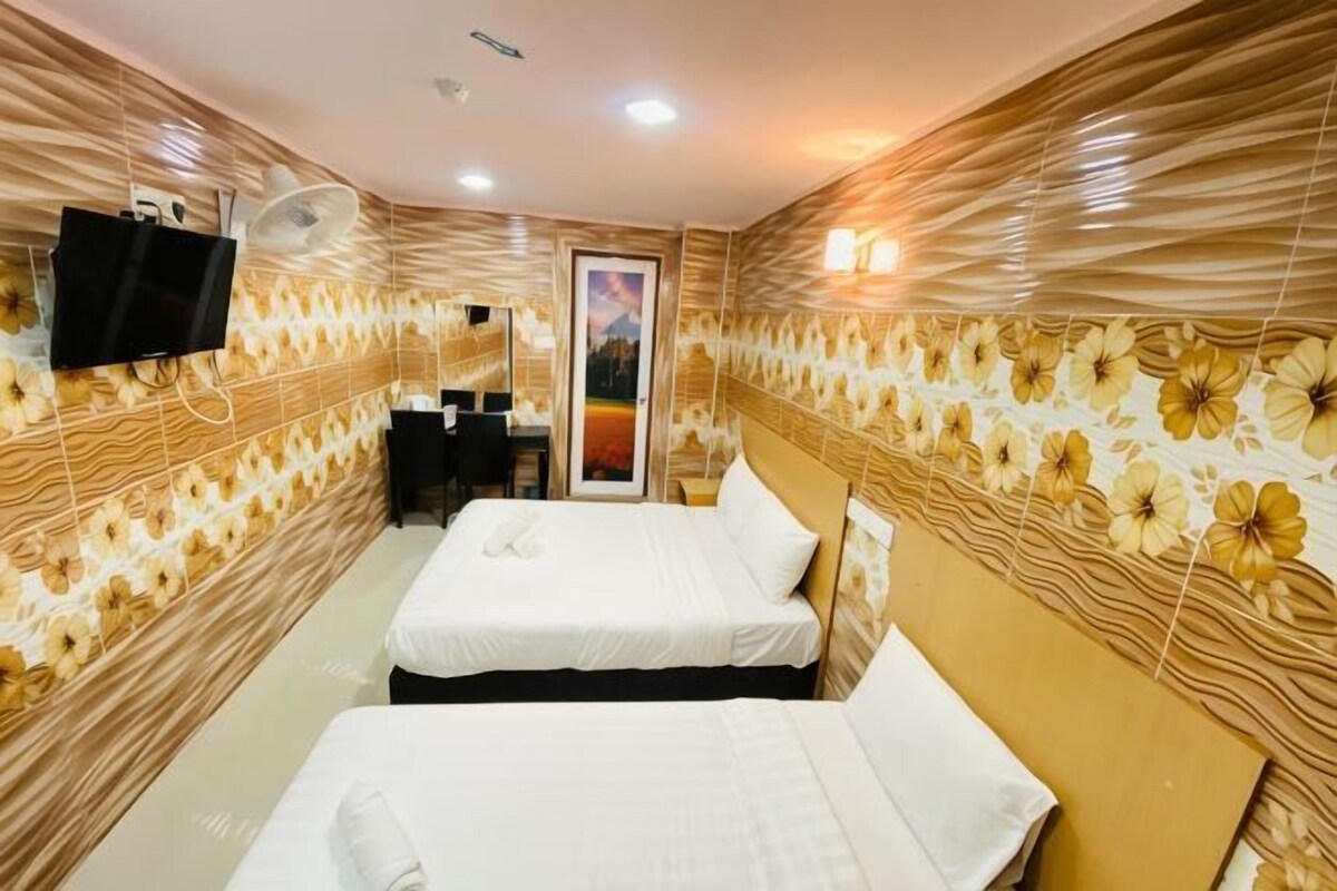 A hotel room with two beds, a flat-screen TV, a desk, and a chair.