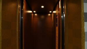 A narrow, dimly lit elevator shaft with a metallic floor and walls, leading to a ceiling with recessed lighting. - CAMERON KEA FARM HOTEL (Brinchang)