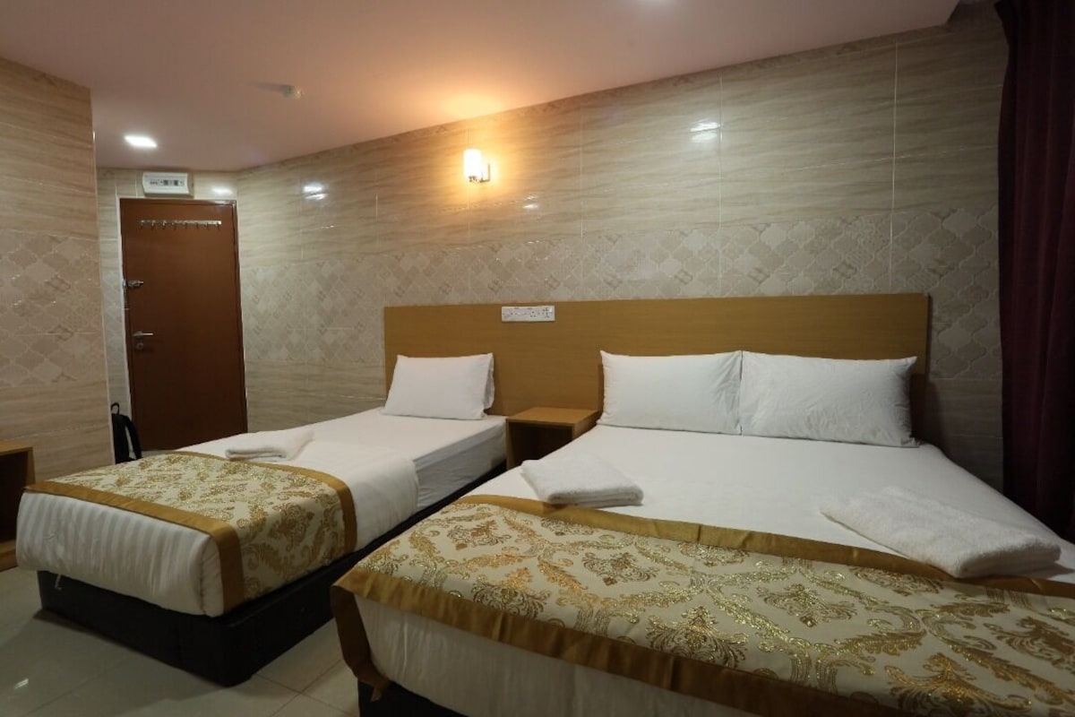A hotel room with two single beds, a wooden headboard, and a small bedside table.