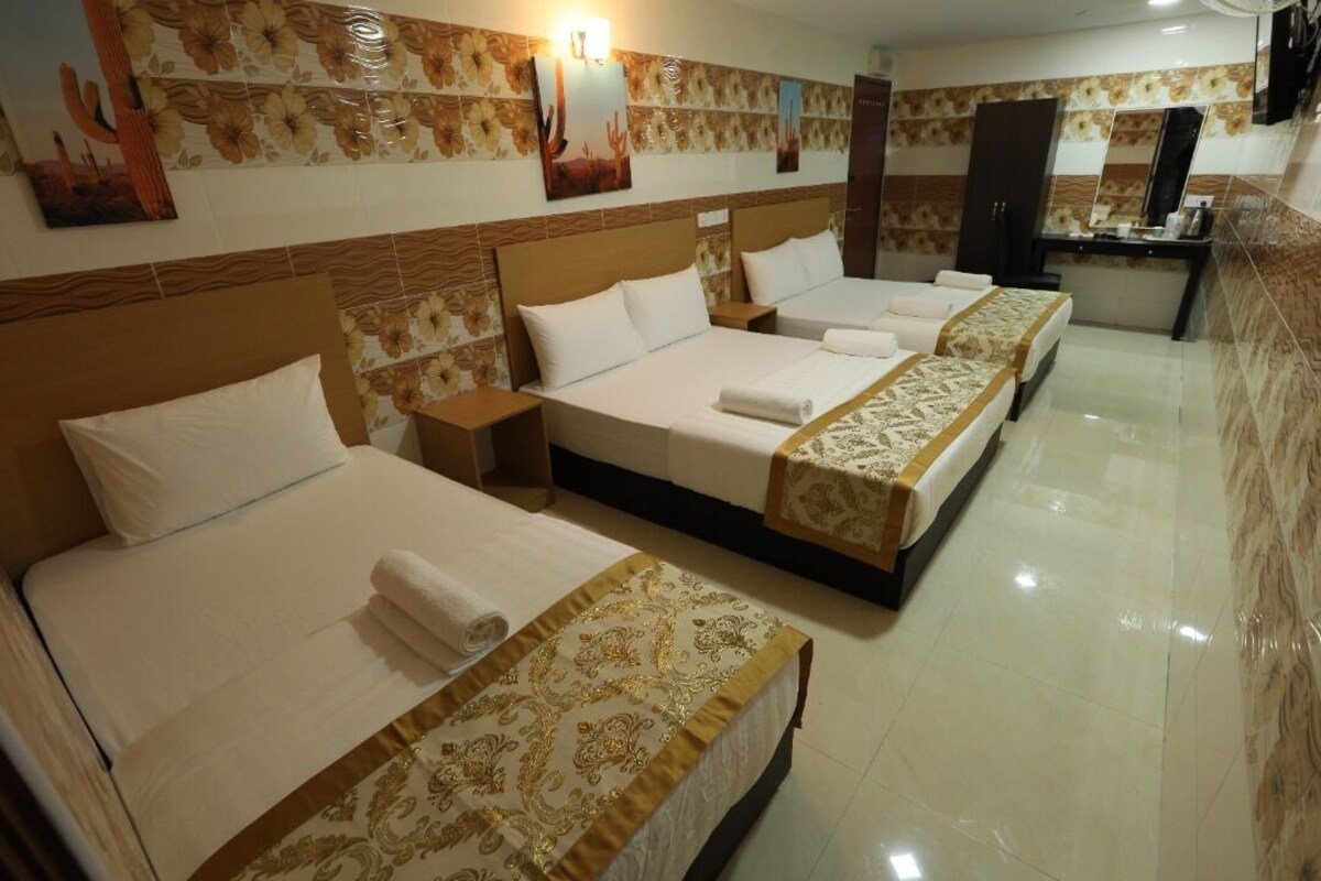 A hotel room with three beds, a vanity, and a mirror.