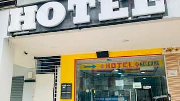 A hotel entrance with a large sign reading "HOTEL" and a welcome sign inside the entrance.