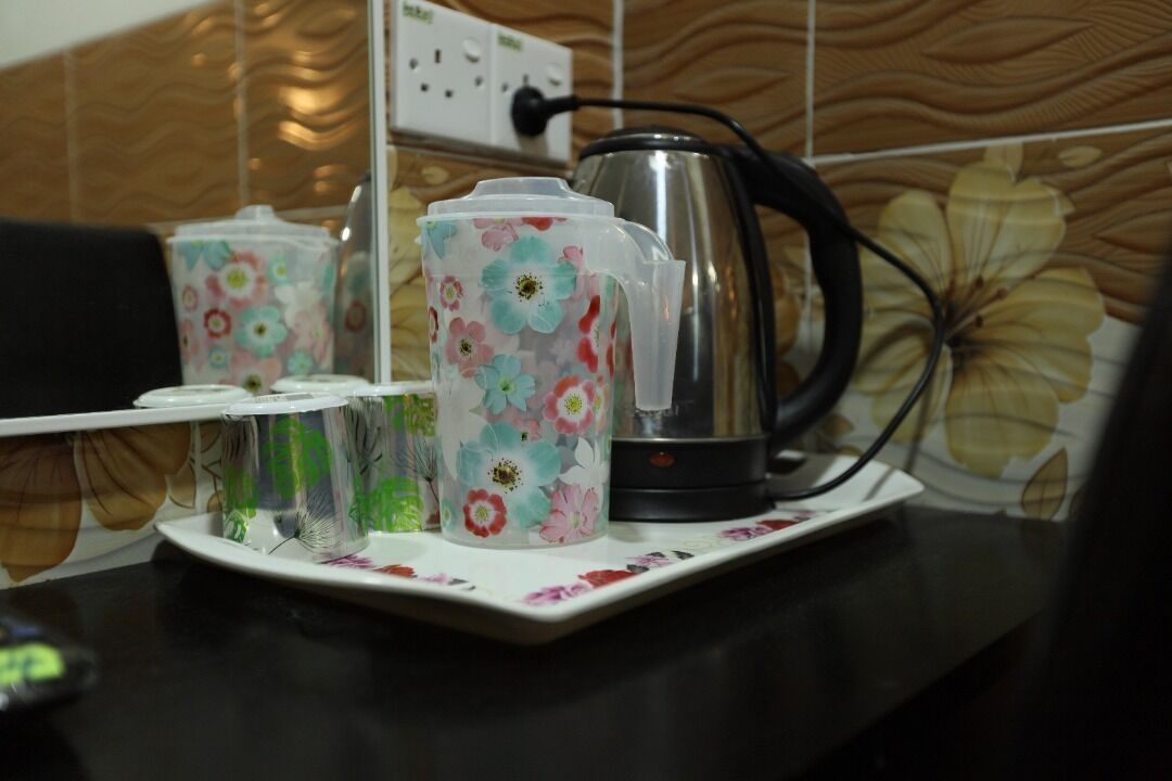 A kitchen counter with a coffee maker, a kettle, and two floral-patterned cups.