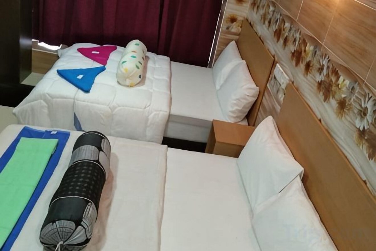 Two single beds with white bedding, a green mat, and a rolled-up black object on the left bed.