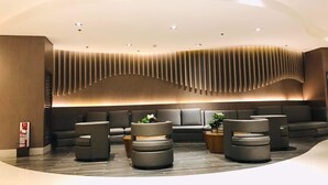 Ein moderner Lounge-Bereich mit einer geschwungenen Sitzgruppe, eingelassener Beleuchtung und einem außergewöhnlichen Wanddesign.