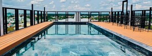 A rooftop infinity pool with wooden deck and metal railings, surrounded by a cityscape view. - Linh Phuong 6 (Can Tho)