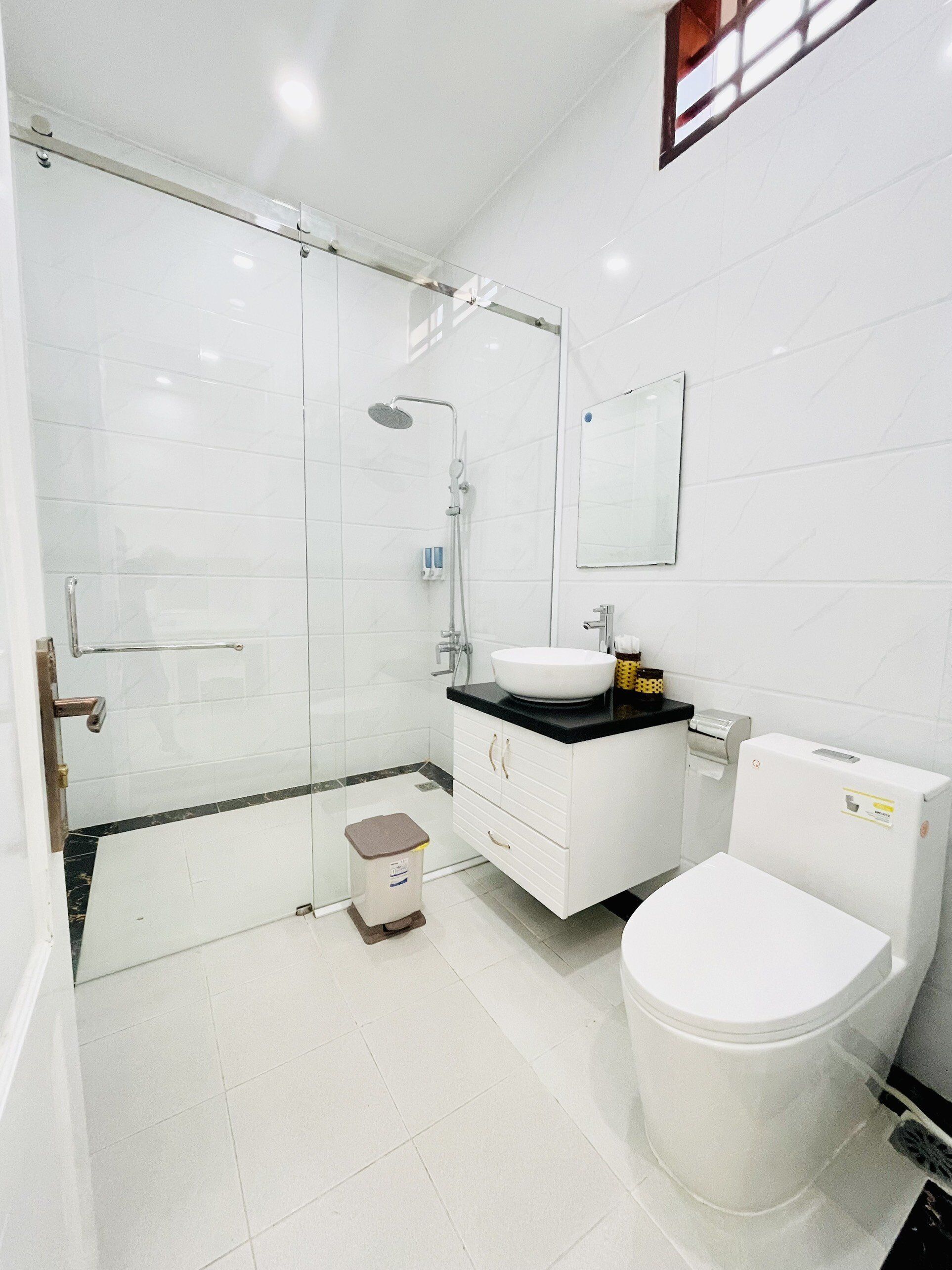 Uma casa de banho moderna com chuveiro em cabine de vidro, uma sanita branca e uma pia.