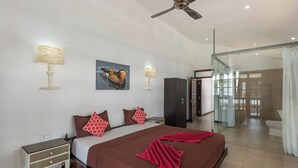Une chambre d’hôtel moderne dotée d’un grand lit, de deux lampes de chevet, d’un ventilateur de plafond, d’une douche en verre et offrant une vue sur l’extérieur.