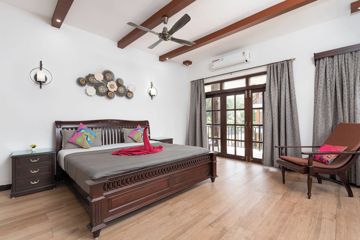 A bedroom with a large bed, a chair, a nightstand, and a ceiling fan.