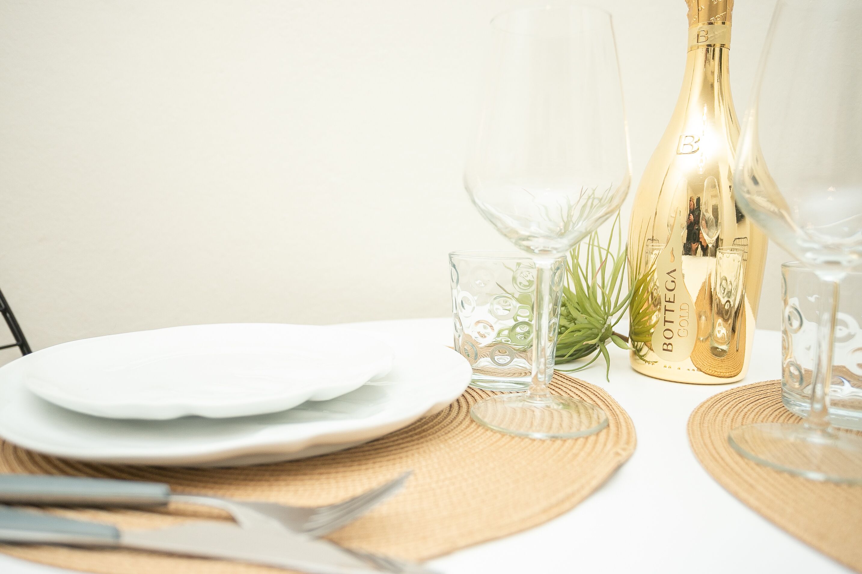 Une table dressée avec de l’argenterie, des couverts et une bouteille de champagne Bottega Gold.
