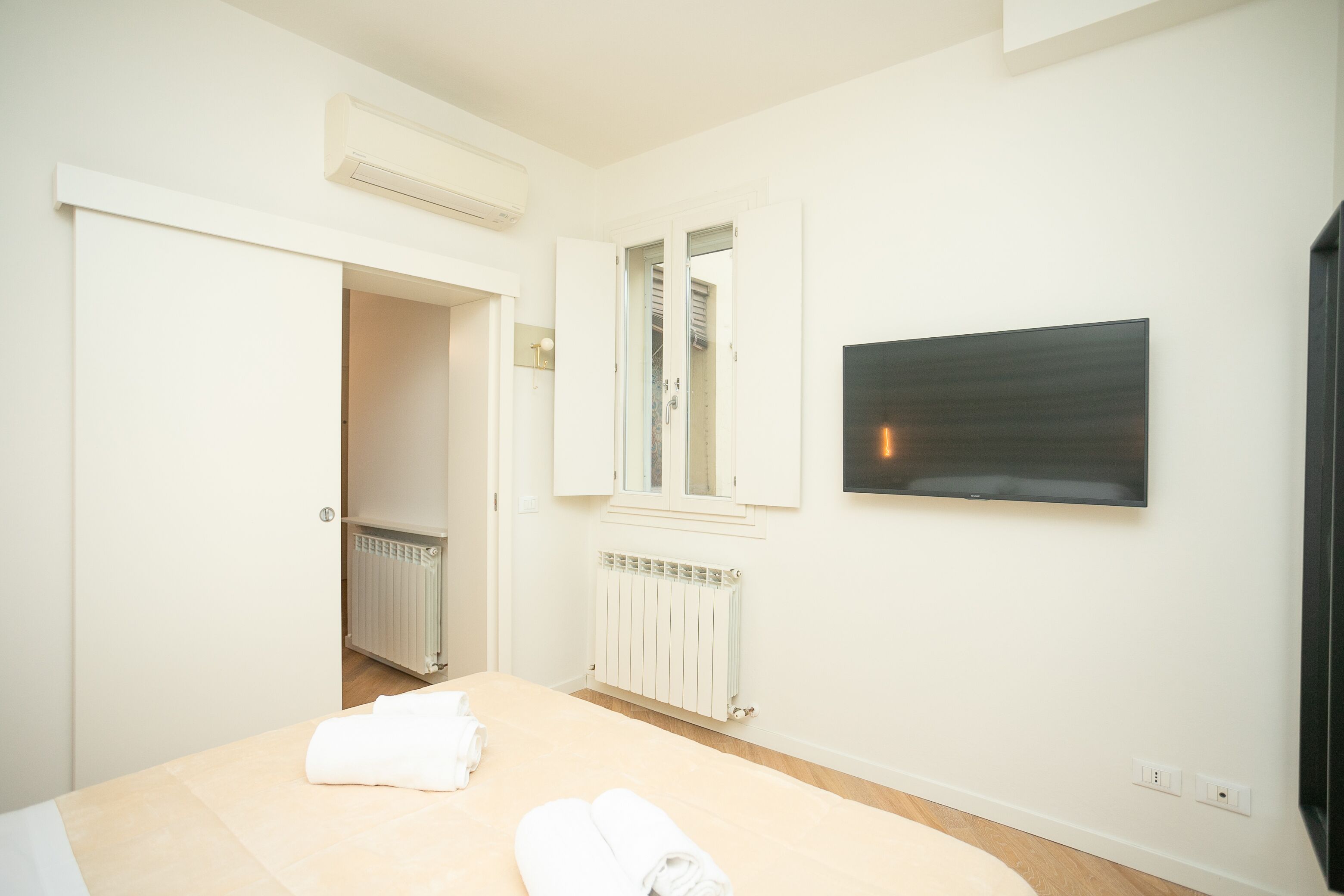 Ein Hotelzimmer mit Bett, Heizkörper, Spiegel und Fernseher an der Wand.