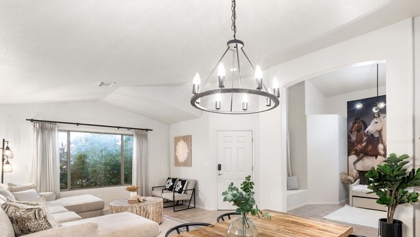 Un amplio salón con una gran mesa de comedor de madera, un conjunto de sofás y una araña.