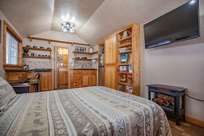 Ein Schlafzimmer mit einem großen Bett, Holzschränken, einem Kamin und einem an der Wand befestigten Fernseher.