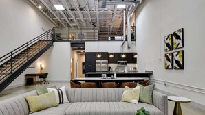 A modern interior with a sectional sofa, a dining area, and a kitchen. - 3BR Luxury Loft Near Downtown & Frost Bank Center (San Antonio)